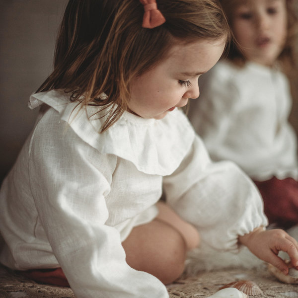 kleines Mädchen mit weißer Bluse spielt auf dem Boden