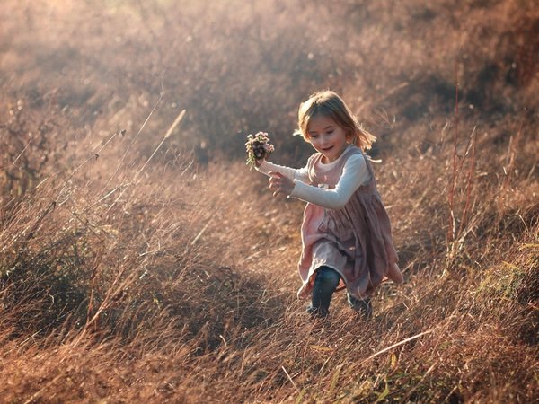 Kind in Leinenkleid rennt über Wiese